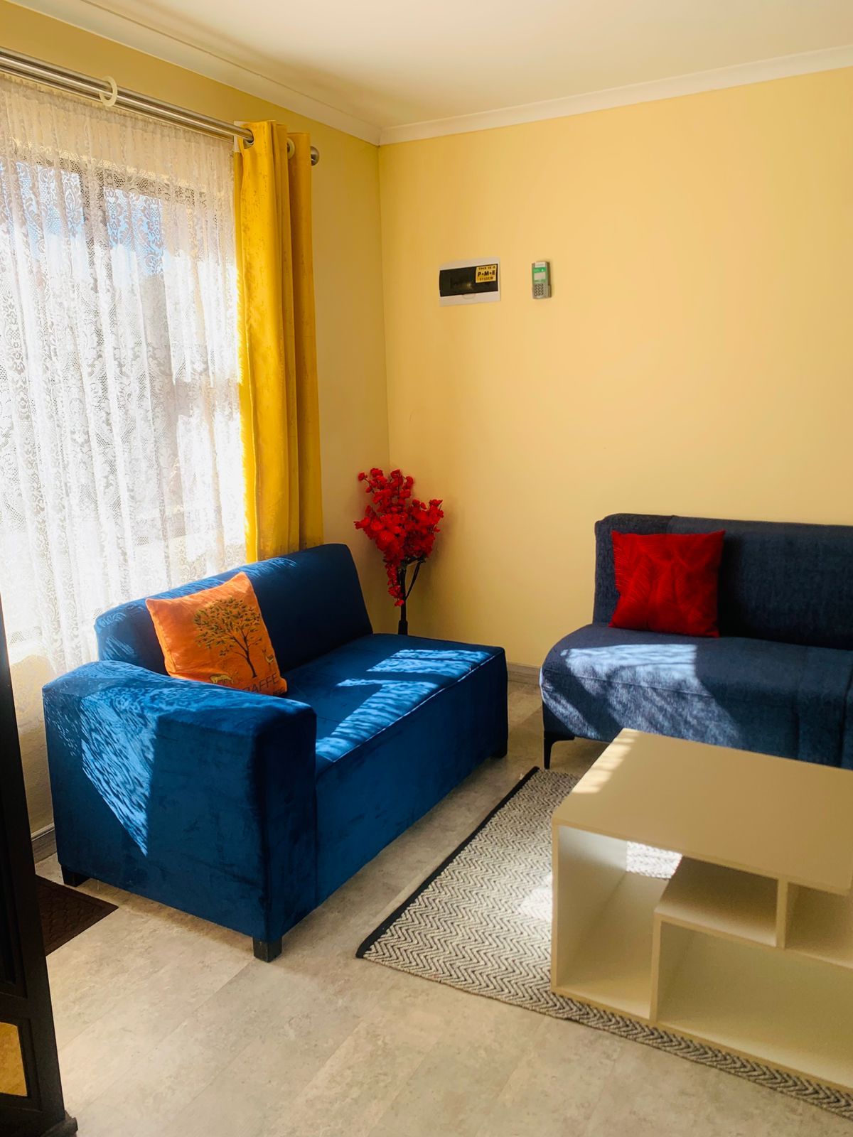 Sunlit Khopolong Estate living room with blue velvet sofas and yellow drapes